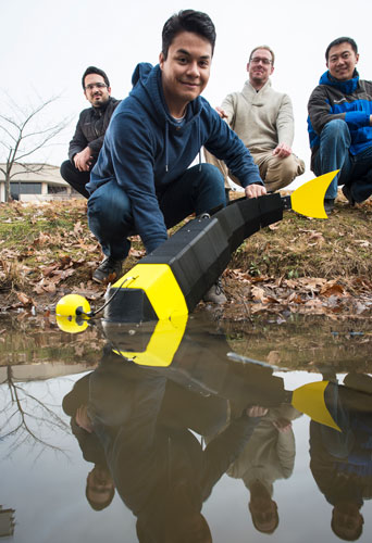 Computer engineers, from left, Morteza Eskandari, Sergio Cruz, Blazej Horyza, and Feitian Zhang, assistant professor in the Department of Electrical and Computer Engineering, prepare to launch a robot fish.