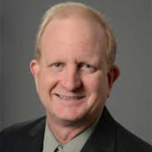 Dr. Randy Howard wears a black suit and colored tie