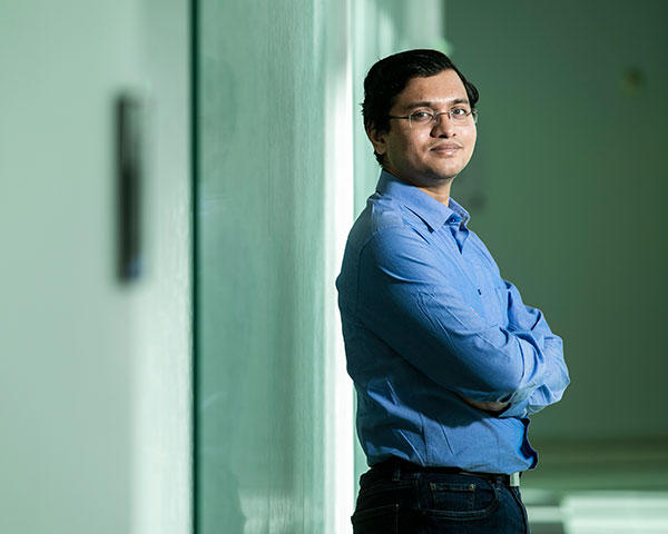 Sai Dinnakaro in a hallway facing the camera in a blue shirt.